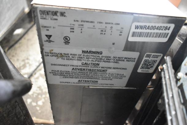 Ovention stainless steel commercial countertop conveyor pizza oven, model S2000T, 208/240 volts, 3 phase, warning label visible.