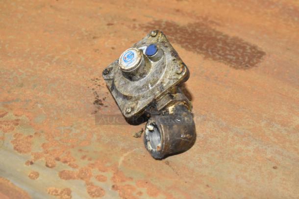 Old, rusty gas control valve on a weathered surface. Stamped markings indicate wear, and the visible blue sticker is partially intact.