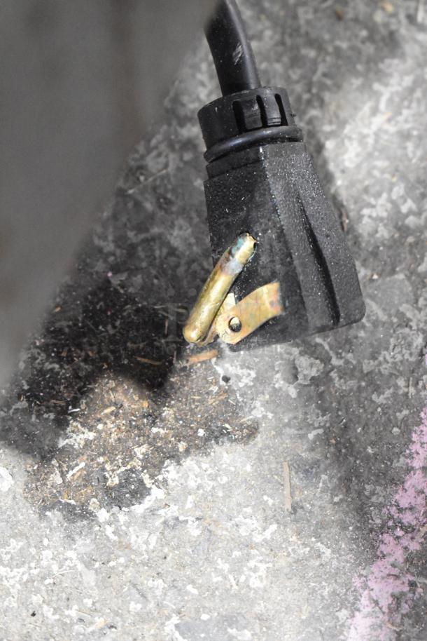 A power plug on a concrete floor, appears worn, indicating electrical use and connectivity for a Hoshizaki appliance.