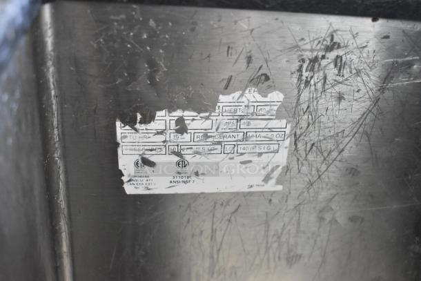 Silver King stainless steel commercial chest cooler or freezer with visible scratch marks and partially legible label. Model on casters.