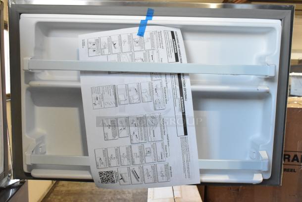 Stainless steel Whirlpool 21MSTFATR6 cooler/freezer, brand new with scratch/dent. Instruction manual visible on door.