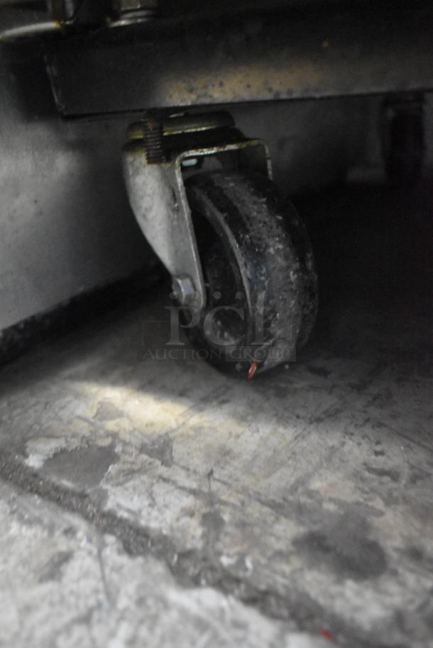 Close-up of caster wheel on True T-35 stainless steel commercial cooler. Caster shows wear; cooler is mobile.