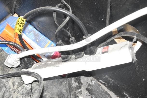 Cables and a power strip on a dusty floor, no cooler present.