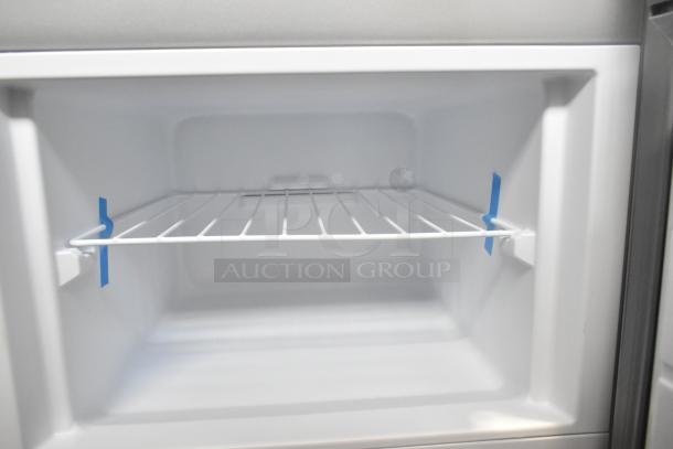 Brand new Frigidaire EFR780-T-6COM stainless steel cooler freezer interior with protective blue tape. Scratch and dent model.