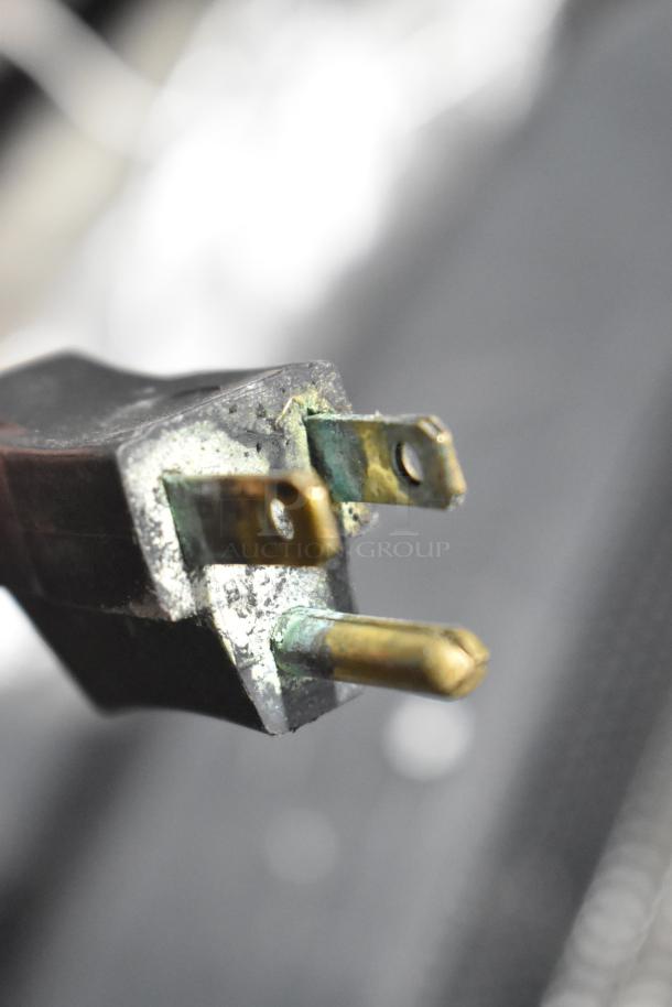 A close-up of a slightly tarnished brass electrical plug, not directly related to the Cleveland braising pan.