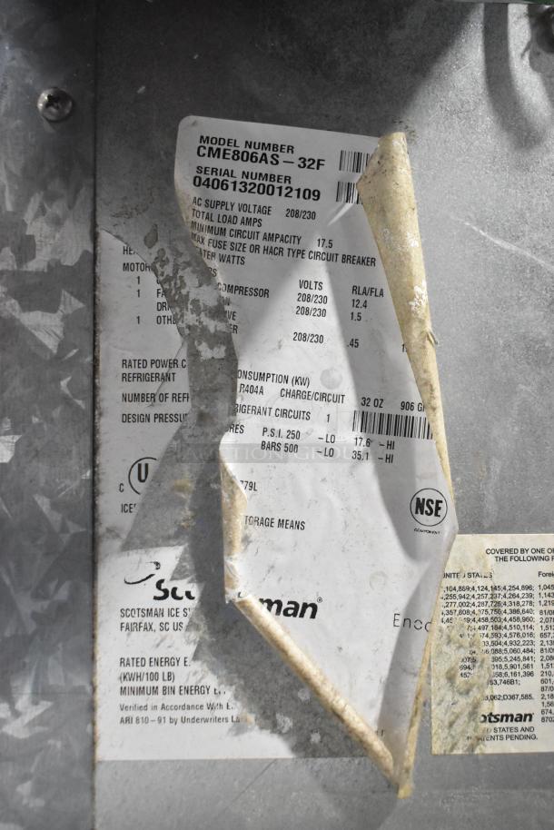 Scotsman CME806AS-32F stainless steel ice machine head label showing model, 208/230 volts, 1 phase information. Signs of wear.