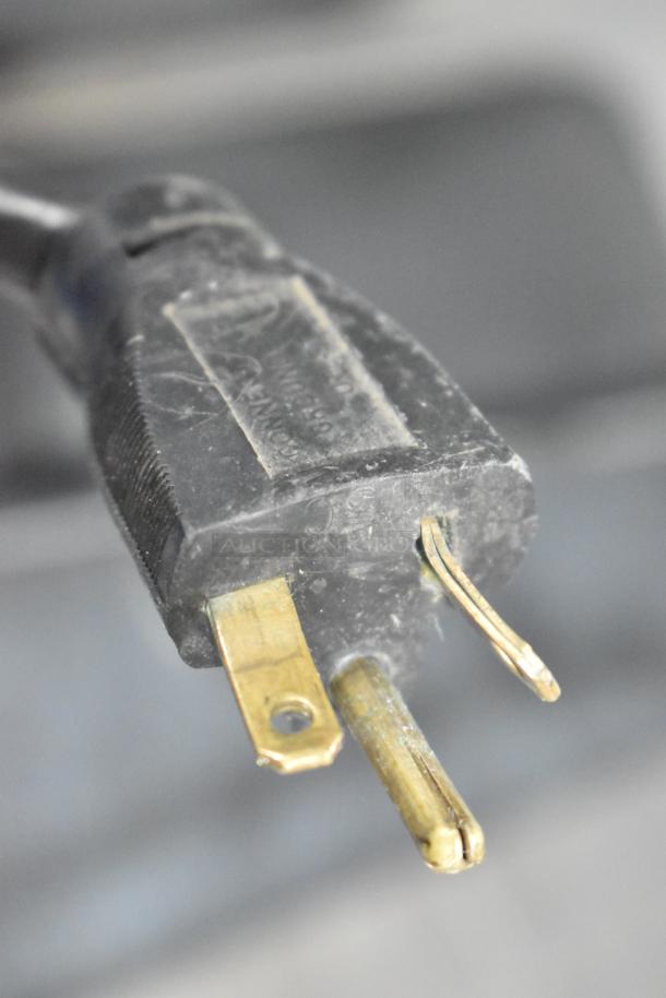 Close-up of a power plug from the Stoelting SF121-38I2 soft serve ice cream machine, showing prongs and slight wear.