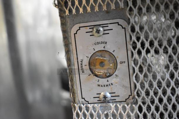 Stainless steel control panel on a commercial work table. Features thermostat dial with settings for colder, warmer, and off.