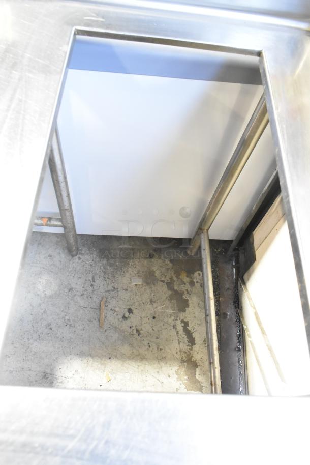 Stainless steel commercial work table with drop-in feature. Powered by 115 volts, 1 phase. Slight surface wear visible.