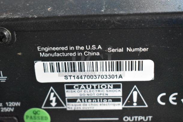 Close-up of serial number ST1447003703301A on electronic device; caution label for electric shock risk; QC passed sticker.