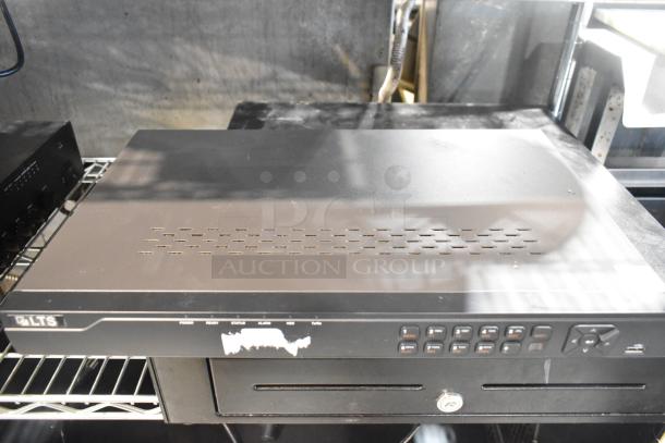 Auction items: LTS security DVR, power and status indicators, black metal cash drawer underneath, good condition.