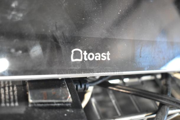 Close-up of a Toast POS monitor with visible branding, part of an auction lot with various POS monitors. Used condition.