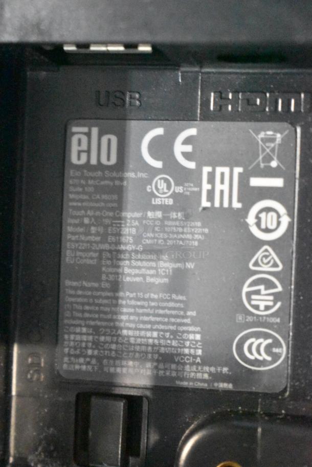 Close-up view of an Elo POS monitor label showing model number, compliance logos, and connectivity ports.