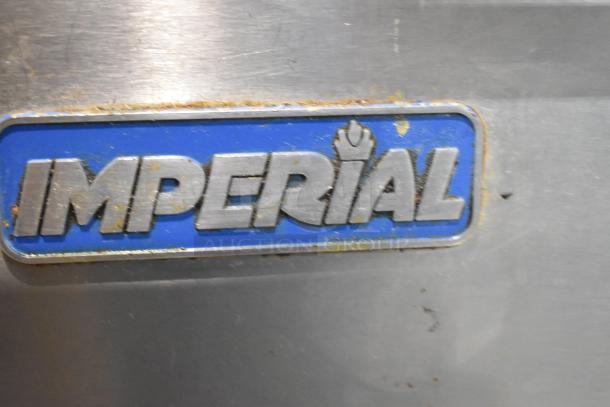 Imperial IR4-612 stainless steel logo on a commercial gas-powered flat top griddle with four-burner range, oven, shelf, and backsplash.
