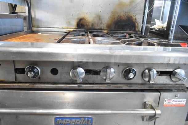 Imperial IR4-612 stainless steel commercial gas griddle with 4-burner range, oven, overshelf, and backsplash. Visible wear.