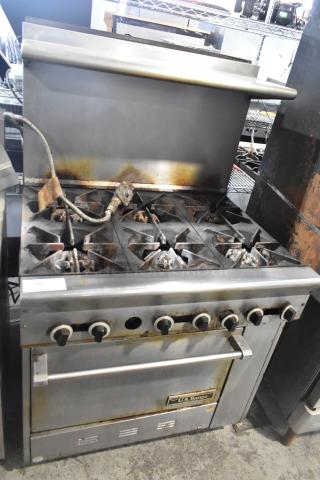 US Range stainless steel commercial gas 6-burner range with oven, overshelf, and backsplash. Used condition with visible wear.