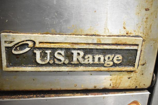 US Range stainless steel commercial gas-powered 6 burner range with oven and shelf. Visible wear and "U.S. Range" label shown.