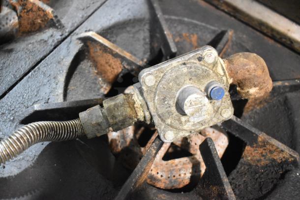 Close-up of gas connection on US Range stainless steel commercial gas-powered 6-burner range with visible rusting.