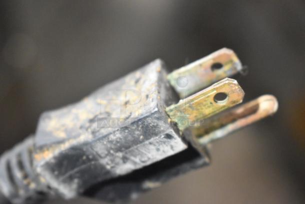 Close-up of a worn, metal-tipped electrical plug with visible dirt and corrosion.