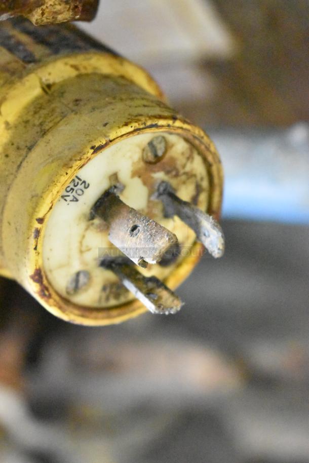 Close-up of a rusty electrical plug with visible 20A 125V markings.