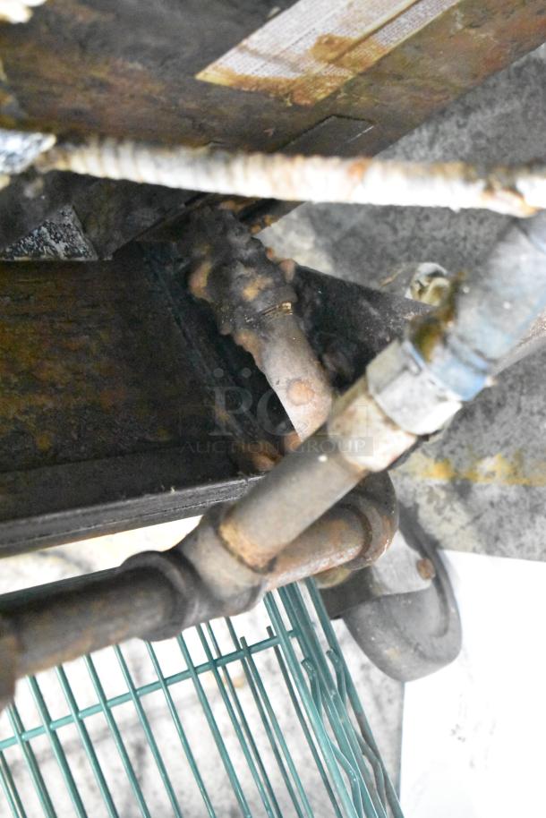 Blodgett commercial gas conduit with visible wear, connecting to green metal racks and commercial casters below.