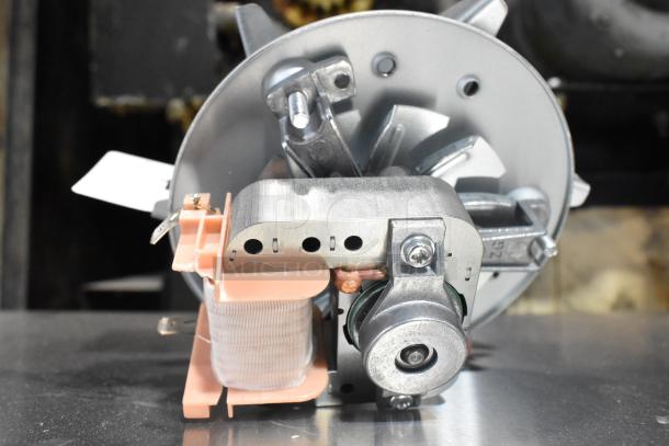 Brand new metal convection oven fan, scratch and dent condition, showcasing motor and blades. Perfect for repairs or replacement.