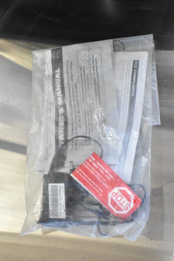 Bag containing owner's manual and FCC compliance documents with visible stop tag and product information label.