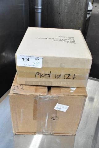 Sealed boxes of TD-MFOLD paper towel dispenser and Escalaade mats, marked as scratch and dent, ready for auction.