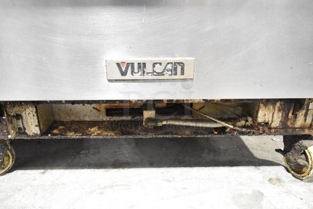 Vulcan V2BG4TS stainless steel griddle with 4-burner range, oven, and backsplash on casters. 50,000 BTU. Visible wear.