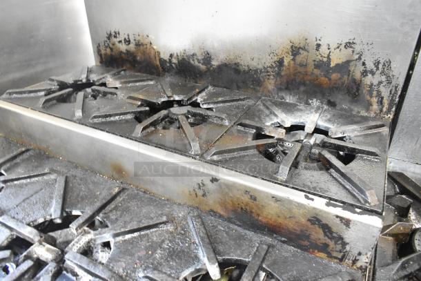 Stainless steel commercial natural gas flat top griddle with 2-tier 6 burner range, oven, and backsplash on casters. 50,000 BTU. Signs of use.