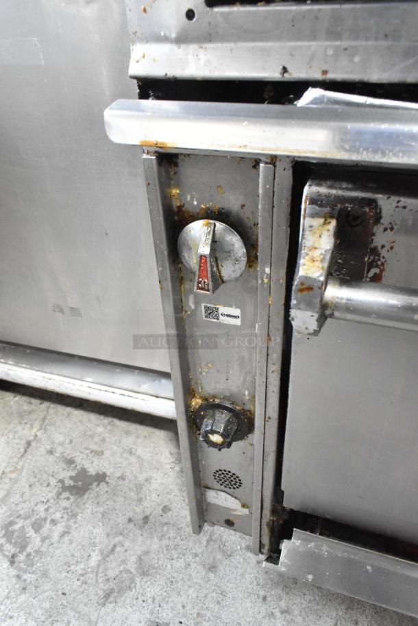 Stainless steel commercial griddle with 2-tier 6 burner range and oven, 50,000 BTU, on casters. Visible wear and rust.