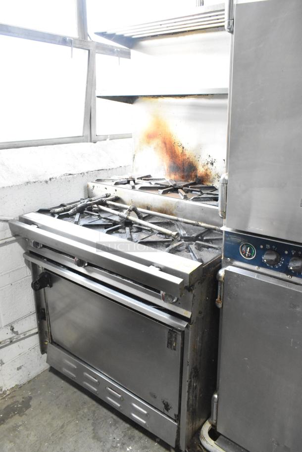 Montague stainless steel natural gas flat top griddle with 2-tier, 6-burner range, oven, and backsplash on casters, 50,000 BTU.