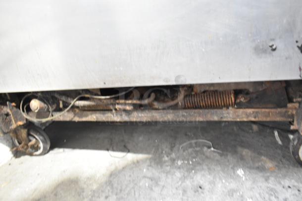 Montague stainless steel commercial flat top griddle with two-tier 6-burner range and oven on casters. Rust visible.