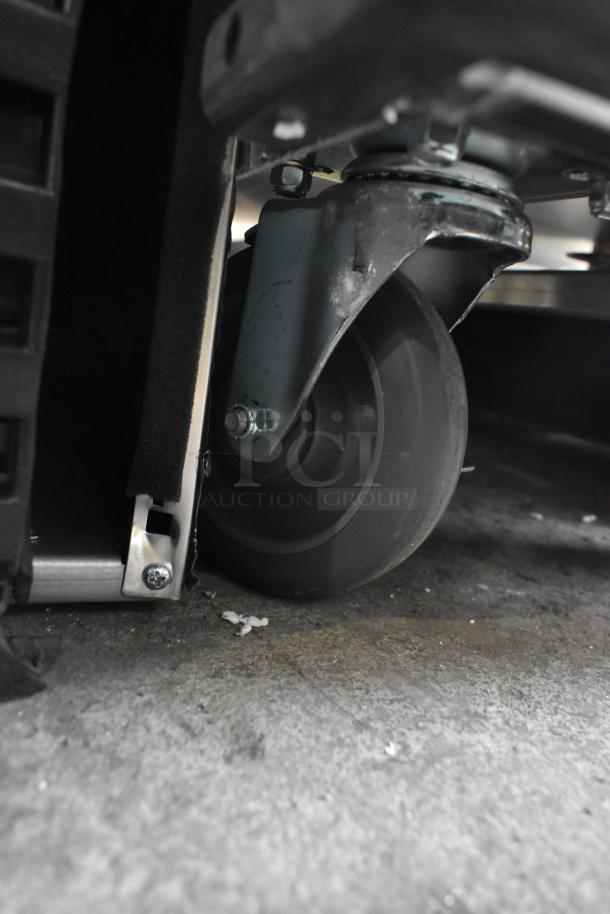 Mainstreet 541CHP1836I heated cabinet wheel on caster, showing metal frame and floor surface. Brand new, scratch and dent condition.