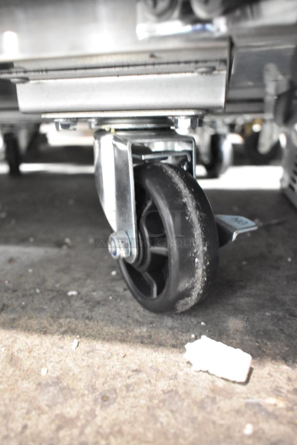 Close-up of caster wheel on a new Avantco 178SSUC27RHC stainless steel undercounter cooler, highlighting mobility.