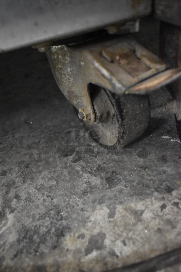 Mono FG180C-UZ52 combi convection oven's commercial caster, worn condition, on concrete floor.