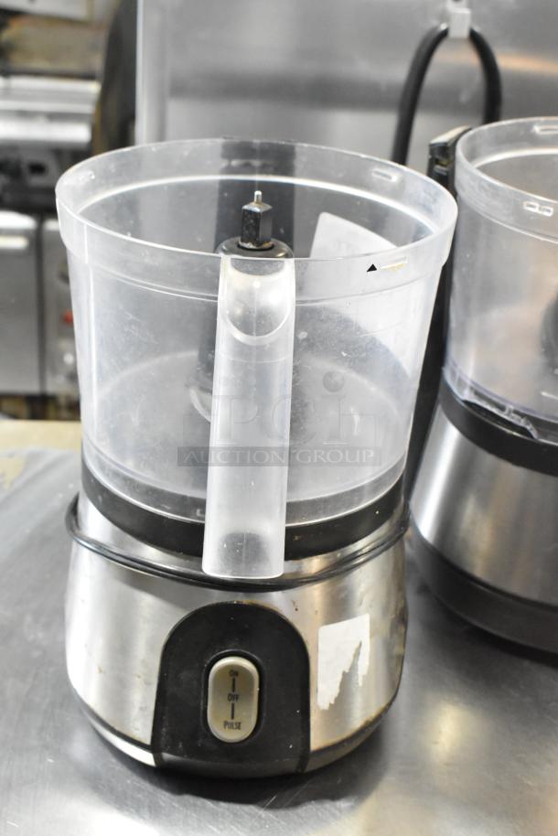Two countertop food processors without lids, stainless steel base, 115 volts, 1 phase. Visible wear on switch label.