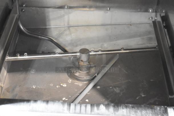 Stainless steel commercial undercounter glass washer interior, showing spray arm and metal finish, in used condition.