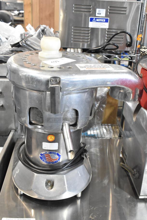 Stainless steel commercial countertop juicer, 115 volts, 1 phase, with visible labels and power cord.