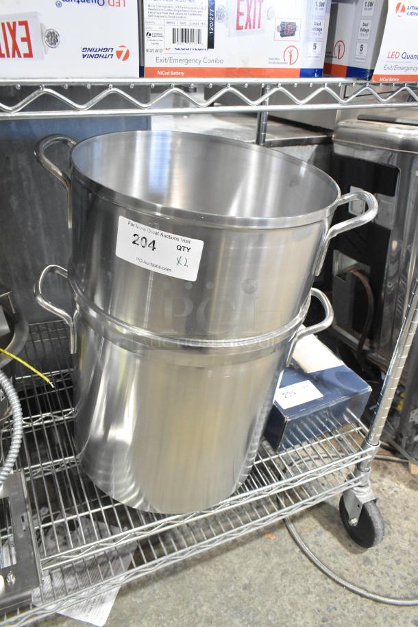 Two brand new stainless steel stock pots, with minor scratches, labeled "204 QTY X2" on shelving unit.