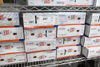 8 new LHQM LED R SD M6 Exit/Emergency Combo Signs in boxes on shelf; features dual voltage, 1.5W LEDs, NiCad battery.