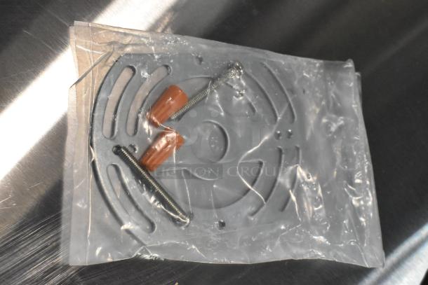Plastic bag containing metal mounting plate, screws, and wire connectors for E185721-B / ASRLED-2-HL emergency light.