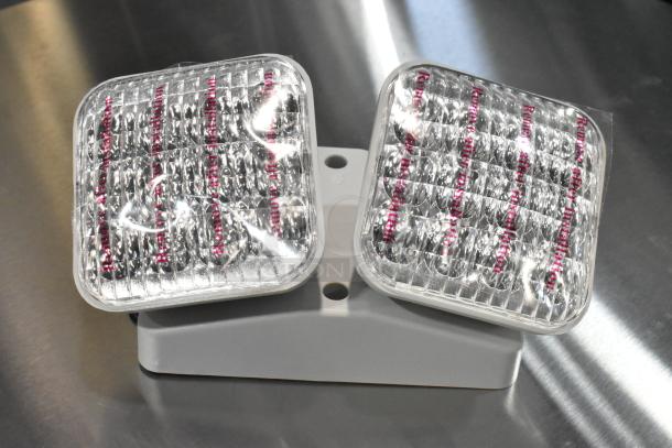 Brand new ASRLED-2-HL/TSR-W-REM emergency light, dual-head, scratch and dent condition, “Remove after installation” label.