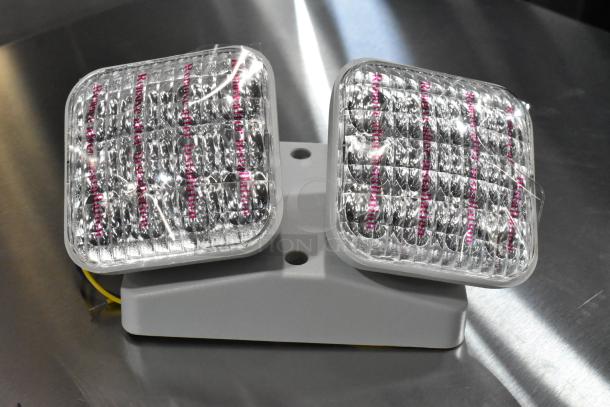 Two ASRLED-2-HL / TSR-W-REM emergency lights in new condition, featuring clear lens covers and protective film.