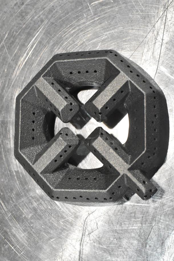 Black Garland US Range 4522271 open burner head with perforations, brand new condition on a scratched metal surface.