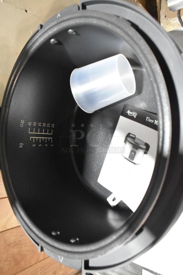 Avantco 177RCSB90 stainless steel electric rice cooker interior with measuring cup and user manual. Capacity markings visible.