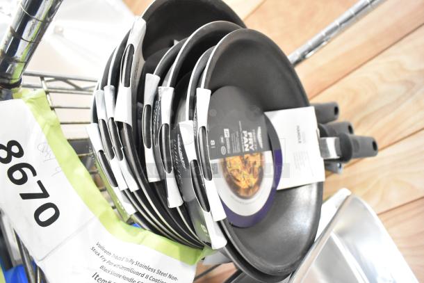 Stack of brand new Vollrath fry pans with CeramiGuard II coating and silicone handles, auction tag visible.