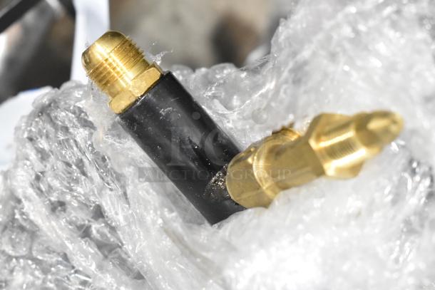 Close-up of a metal propane gas burner connector wrapped in plastic. Scratch and dent condition visible.