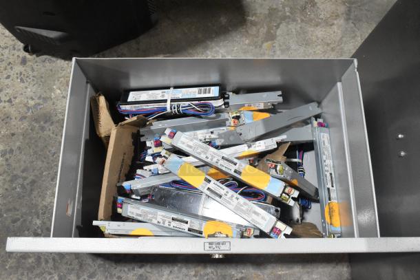 Metal drawer with new scratch and dent condition, containing various Advance ballasts with visible labels and wiring.