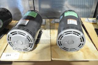 2 US Motors FK75 condenser fan motors, 208-230/460V, 3-phase, mounted on wooden base, visible labels and cooling vents.
